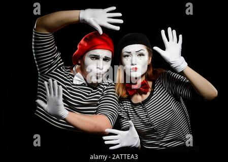 Funny mime artists on black. Striped shirts, white gloves and berets Stock Photo