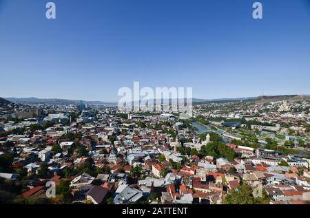 Panoramic wide angle view of Tbilisi from Sololaki Hill, with the Kura river crossing the city center and mountains in the background  (Georgia) Stock Photo