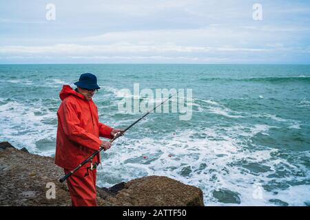 Portrait of an old man fishing in the sea. Fishing concept. Stock Photo