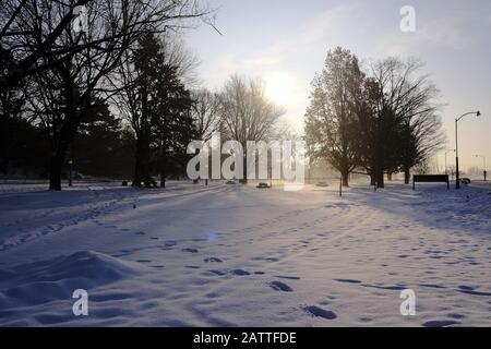 Gorgeous pale sunrise seen through the trees in a very snowy Commissioners Park, Ottawa, Ontario, Canada. Stock Photo