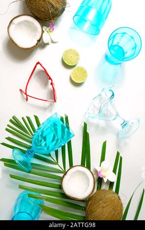 Coconut summertime entertaining theme flat lay creative layout overhead with shadows from blue drinking glasses cast over table. Stock Photo