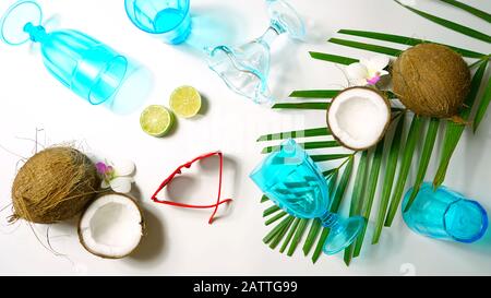 Coconut summertime entertaining theme flat lay creative layout overhead with shadows from blue drinking glasses cast over table. Stock Photo