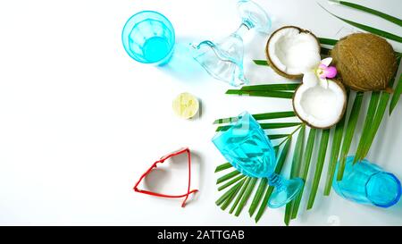 Coconut summertime entertaining theme flat lay creative layout overhead with shadows from blue drinking glasses cast over table. Stock Photo