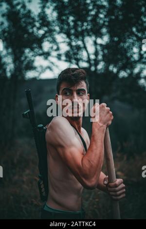 The young revolutionary member or member of the mafia gang is doing dirty work. He's looking around with a gun behind him. Mafia Concept. Stock Photo