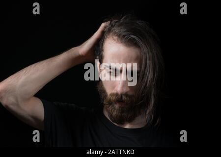Hipster man solves a problem and thinks. Shot on black isolated background. Thinks Concept. Stock Photo