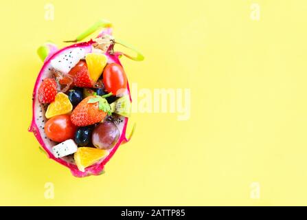 Fruit salad bowl served in a dragon fruit and vegetables healthy organic food fresh summer fruits tropical on yellow background , top view copy space Stock Photo