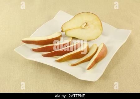 Fresh raw red anjou pear slices and half on white plate Stock Photo