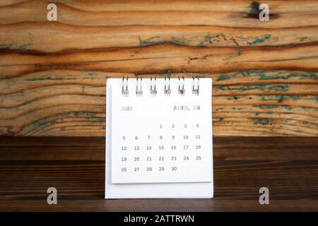 2020 April. White paper calendar on a wooden table. Time planning, day counting and holidays Stock Photo
