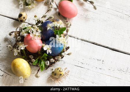 Colored Easter eggs and spring flowers on a white wooden background. Copy space. Stock Photo