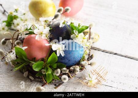 Colored Easter eggs and spring flowers on a white wooden background. Copy space. Stock Photo