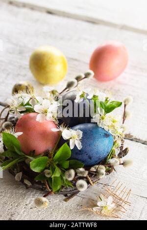 Colored Easter eggs, willow branches and spring flowers on a white wooden background. Stock Photo