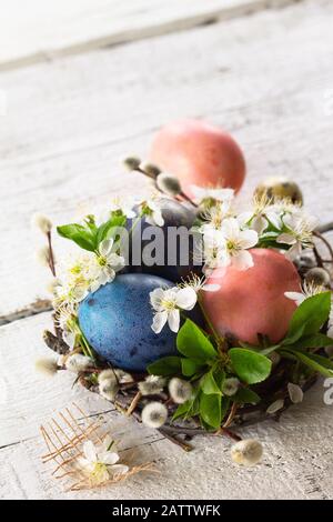Colored Easter eggs, willow branches and spring flowers on a white wooden background. Copy space. Stock Photo