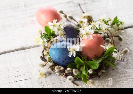 Colored Easter eggs and spring flowers on a white wooden background. Copy space. Stock Photo