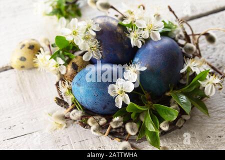 Colored Easter eggs close-up, willow branches and spring flowers on a white wooden background. Stock Photo