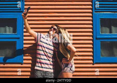 Young beautiful caucasian people couple take a slefie picture together with a kiss and smile - technology and social media pictures concept - coloured Stock Photo