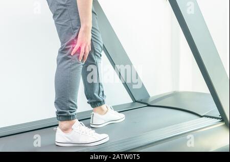 knee pain, close up young man suffer knee pain during run on treadmill, Sport exercising injury Stock Photo