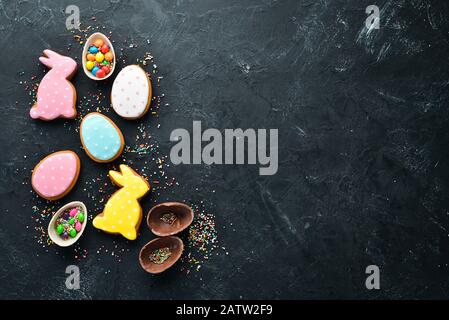 Easter greeting card. Happy Easter. Easter gingerbread cookies and decorative colored eggs. On a black background. Top view. Free copy space. Stock Photo