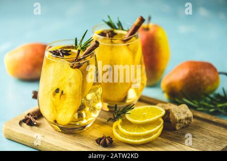 Festive summer drinks, pear spice cocktail. Hot drink cocktail for Christmas, winter or autumn holidays. Served with ingredients on light blue surface Stock Photo