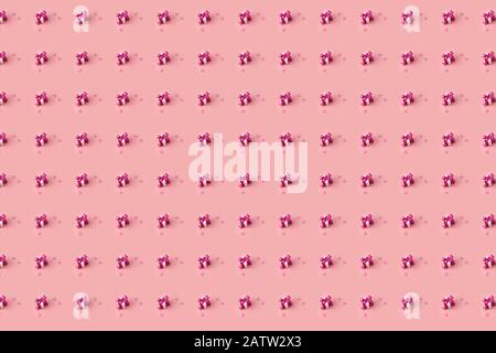 creative pattern tiny gift boxes decorated with pink satin bows and pink hearts on a pastel pink background Stock Photo