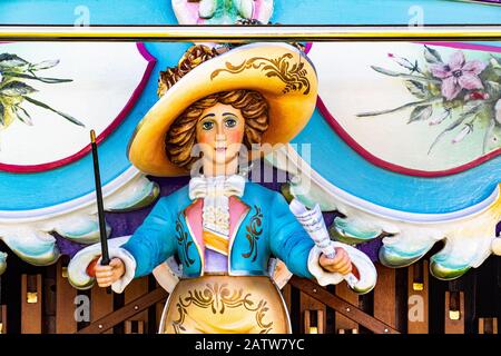 Close up Detail of a Brightly Painted Female Figurine Holding a Conductors Baton and Sheet Music on a Vintage Mechanical Fair Organ. Stock Photo