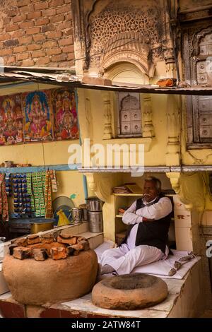 India, Rajasthan, Shekhawati, Ramgarh, man sat beside tandoor in nan bread stall outside old haveli Stock Photo