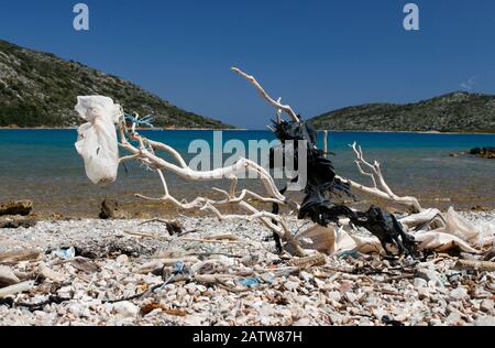 Driftwood with plastic bags and other rubbish on pebble beach, Ormos Planitis, Pelagonisi (Nisos Kyra Panagia), Sporades, Greece Stock Photo