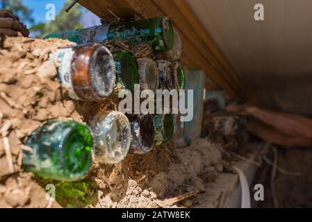 Bottle wall and cob, ecologycal, recycling building techonology. Traditional cob wall construction with colorful bottles. Eco-friendly, sustainable ho Stock Photo