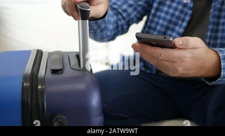 Man Traveling in Holiday Text Using a Mobile Phone, Person with Smartphone in Hand Waiting for a Travel Stock Photo