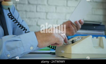 Businessman Working in Office Making a Phone Call from an Old Telephone Stock Photo