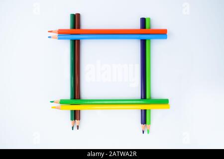 A Border-frame made of eight different colored pencil crayons isolated on a white background Stock Photo