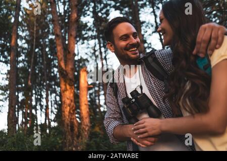 Happy couple is hiking in forest in afternoon. Stock Photo