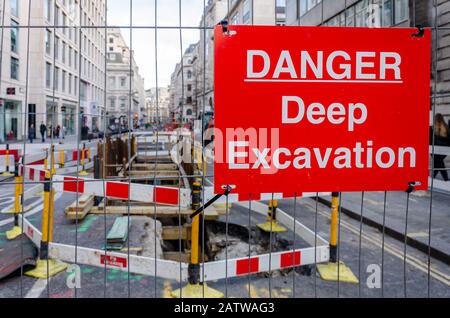 Railings, barriers and warning signs keep people away from a deep excavation in some roadworks in a street in London, UK Stock Photo