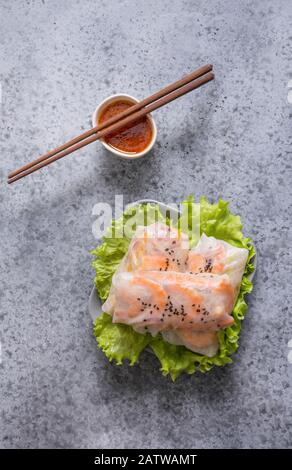 Vietnamese food spring rolls with vegetables, noodles, shrimps in rice paper on grey. View from above. Asian cuisine. Space for text. Vertical format. Stock Photo