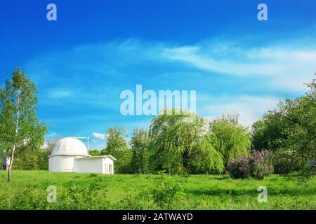 Summer landscape with white ruined astronomy building by blue sky. Old Astronomical Observatory of Lviv University in Ukraine, sunny light day in gard Stock Photo