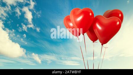 Group of heart shaped red air baloon on blue sky with clouds. Valentines day and romance concept Stock Photo