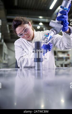 Young woman lab technician in blue rubber gloves with 3D printer on defocused background Stock Photo