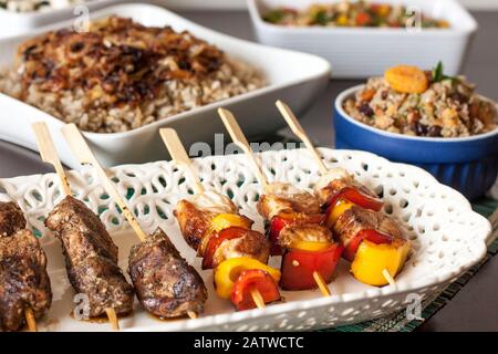 Beef and chicken with vegetable kebabs on white palte, with rice with lentils on the background Stock Photo