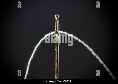 thread stuck in a needle close-up on a black Stock Photo