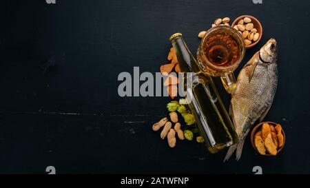 A selection of beer and snacks. Light beer, dark beer, live beer. On a black wooden background. Free space for text. Top view. Stock Photo
