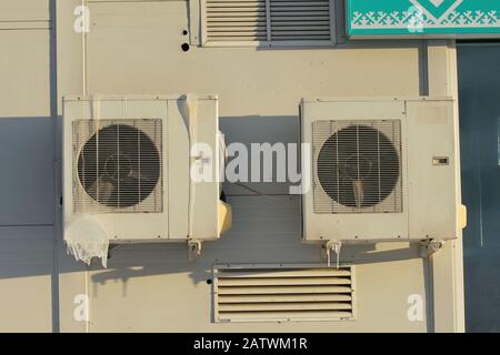 Two air conditioners on a white wall with icicles. Stock Photo