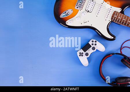 Electric guitar, joystick, headphones. Pop culture media attributes. Top view. Stock Photo