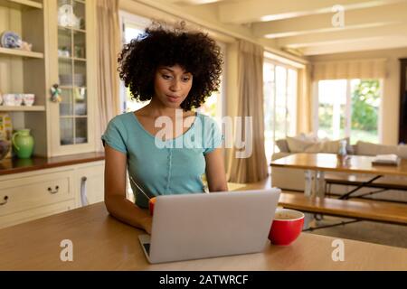 Young woman using computer in the kitchen Stock Photo