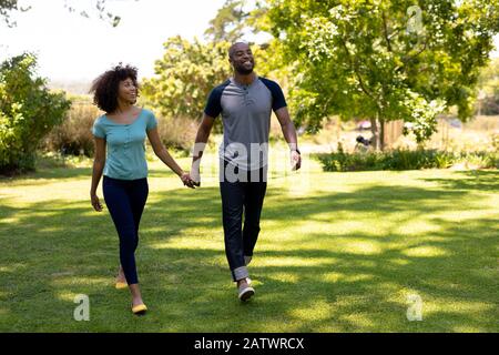 Happy young couple walking hand in hand in the garden Stock Photo