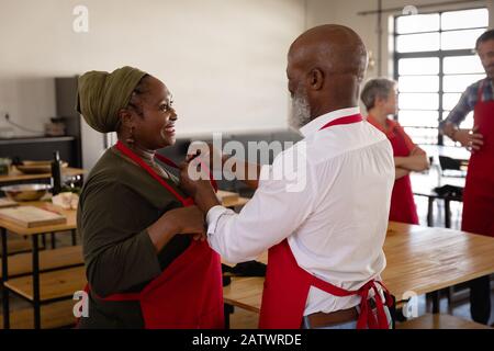 African man helping an African woman to put on her apron Stock Photo