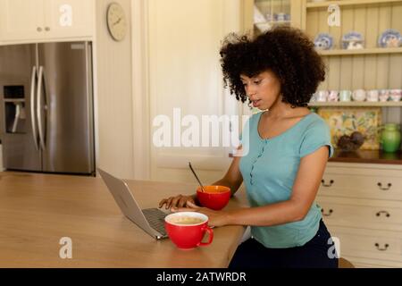 Young woman using computer in the kitchen Stock Photo