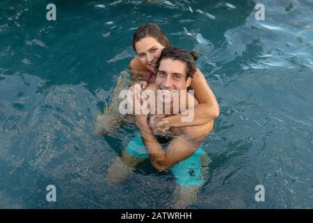 Happy young couple holding each other in the swimming pool Stock Photo