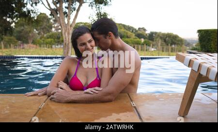 Happy young couple holding each other in the swimming pool Stock Photo