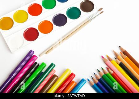 Set of tools for painting - colored pencils, felt-tip pens, watercolor paints and brushes close-up on a white background, copy space for text Stock Photo
