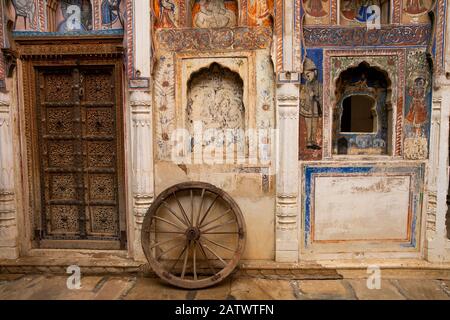 India, Rajasthan, Shekhawati, Dundlod, Tunanram Goenka (seth rus Das) Haveli, restored home of wealthy merchant, courtyard, wheel between decorated do Stock Photo