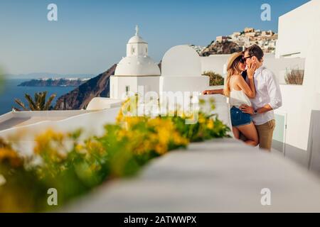 Santorini, Greece honeymoon. Couple in love walking and kissing in Fira. Husband and wife enjoying sea landscape. Stock Photo